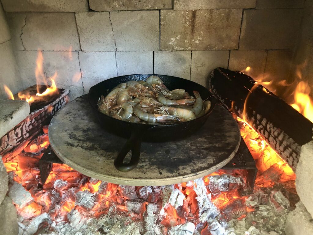 Cooking shrimp in a cast iron pan over fire.