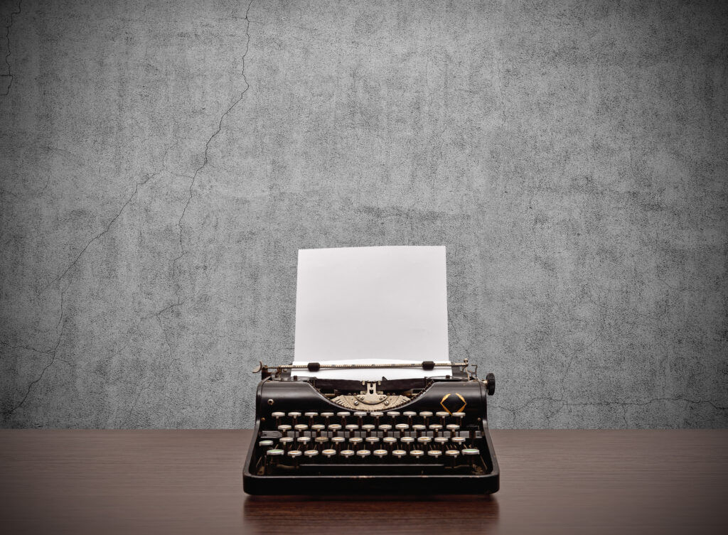 Old typewriter with blank paper on wooden table